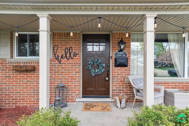 view of exterior entry with a porch and brick siding