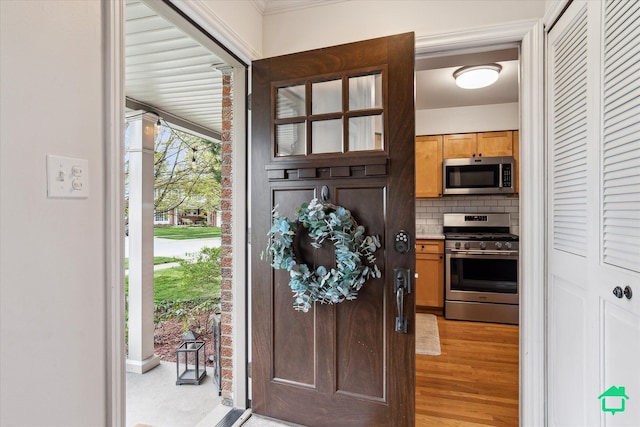 foyer featuring ornamental molding and light wood-style flooring