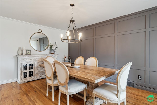 dining room featuring visible vents, light wood-style floors, an inviting chandelier, ornamental molding, and a decorative wall
