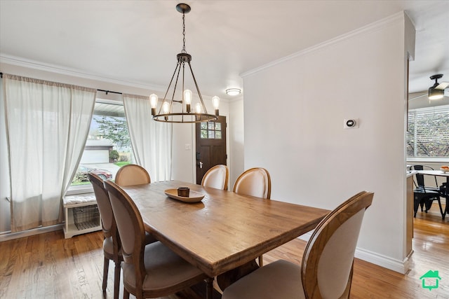 dining room featuring light wood finished floors, ornamental molding, a notable chandelier, and baseboards