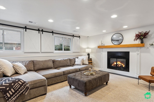 living area with a glass covered fireplace, visible vents, a barn door, and recessed lighting