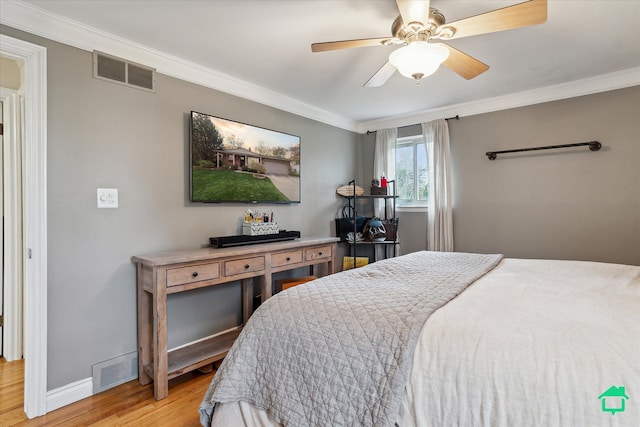 bedroom featuring baseboards, visible vents, wood finished floors, and crown molding