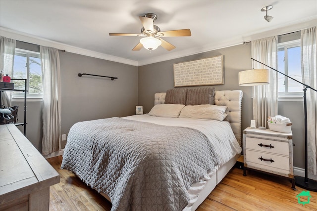 bedroom featuring crown molding, ceiling fan, baseboards, and light wood-type flooring