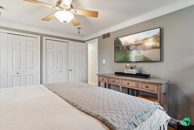 bedroom with ornamental molding, visible vents, ceiling fan, and multiple closets