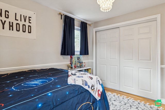 bedroom with a chandelier, light wood-type flooring, and a closet