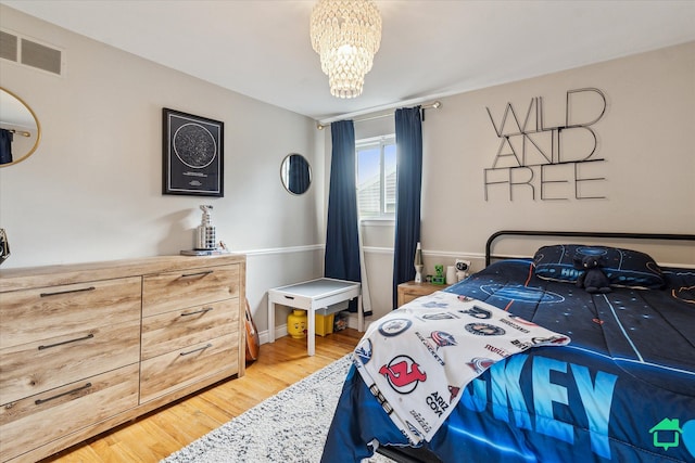 bedroom featuring visible vents, a notable chandelier, and light wood-type flooring
