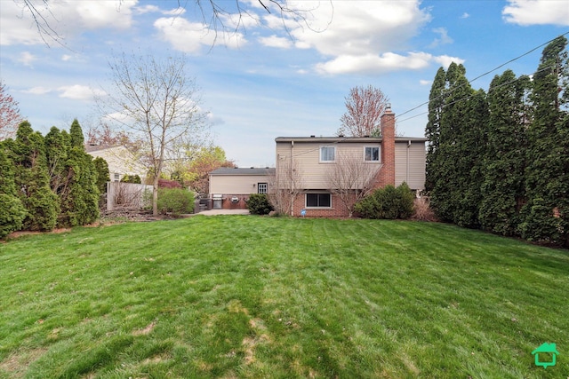 rear view of house with a lawn, fence, brick siding, and a chimney