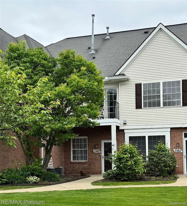 3380 Kneeland Cir, Howell, MI 48843 - view of front of property featuring brick siding, roof with shingles, a front lawn, and a balcony