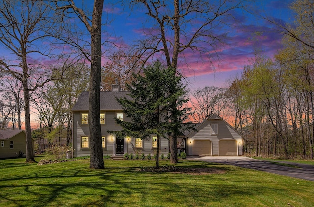 colonial home featuring a lawn, driveway, and a chimney