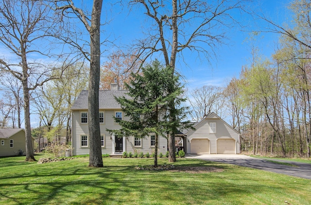 colonial-style house with aphalt driveway, a chimney, a front yard, and a garage