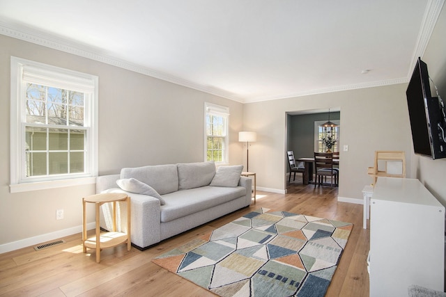 living room featuring visible vents, ornamental molding, and light wood-type flooring