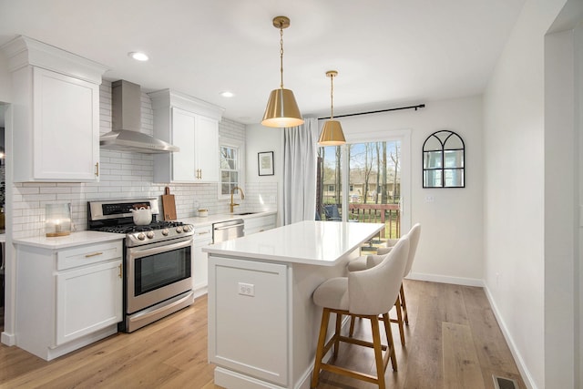 kitchen with wall chimney range hood, appliances with stainless steel finishes, tasteful backsplash, a center island, and white cabinetry