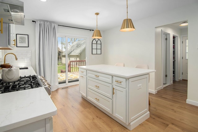 kitchen featuring tasteful backsplash, decorative light fixtures, light wood-style flooring, and white cabinets