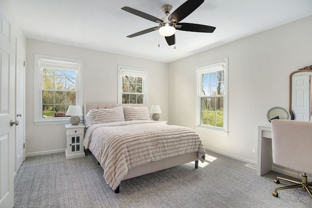 carpeted bedroom featuring baseboards, multiple windows, and a ceiling fan