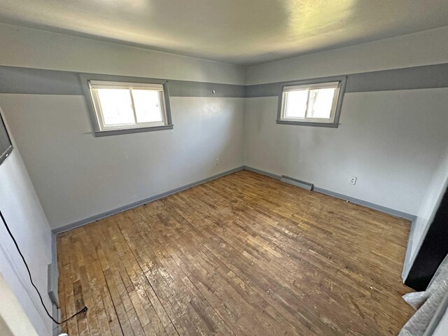 2086 Sloan Rd, Burt, MI 48417 - unfurnished bedroom featuring hardwood / wood-style floors, baseboards, a baseboard heating unit, and multiple windows