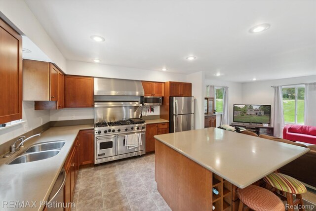 11520 Weiman Dr, Pinckney, MI 48169 - kitchen with stainless steel appliances, a sink, wall chimney range hood, brown cabinetry, and open floor plan