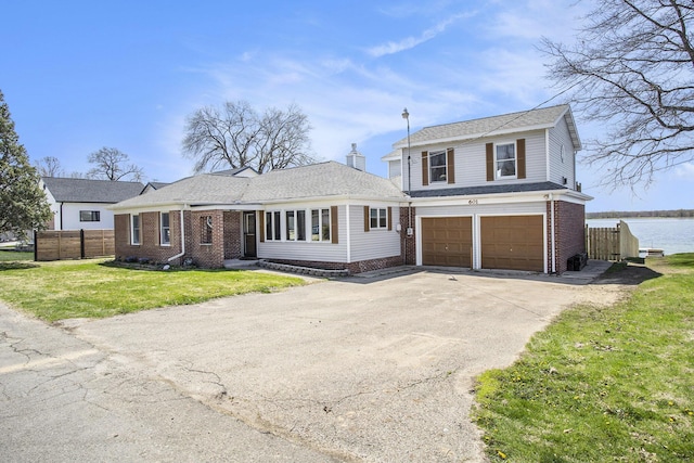view of front of home with concrete driveway, fence, brick siding, a front lawn, and a garage