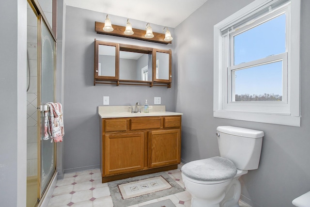 bathroom featuring tile patterned floors, a shower stall, toilet, vanity, and baseboards