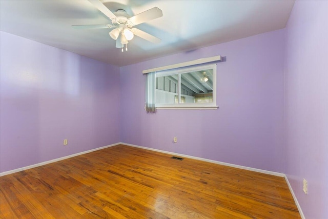spare room featuring a ceiling fan, visible vents, wood finished floors, and baseboards