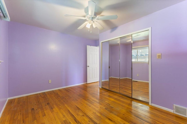 unfurnished bedroom with wood finished floors, a closet, ceiling fan, baseboards, and visible vents