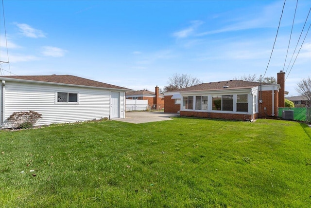 rear view of house with a lawn, fence, central AC unit, and a patio area
