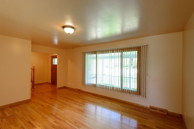 spare room with baseboards, visible vents, and light wood finished floors