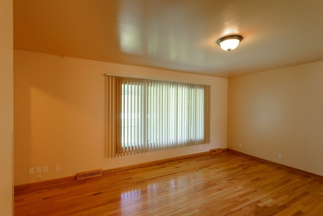 unfurnished room with visible vents, baseboards, and wood finished floors