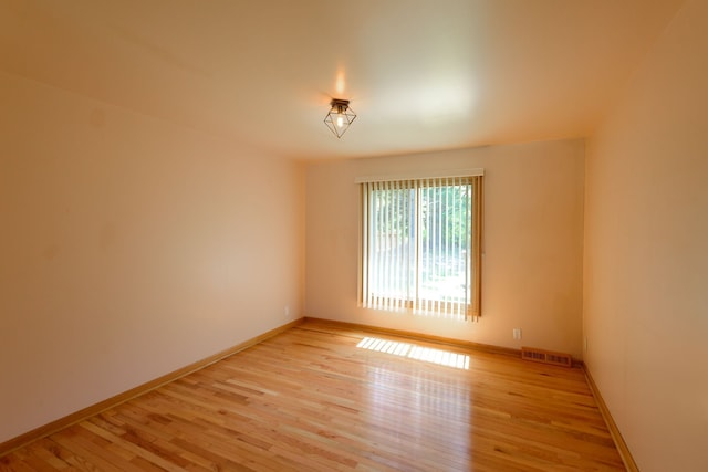 spare room with light wood-style floors, baseboards, and visible vents