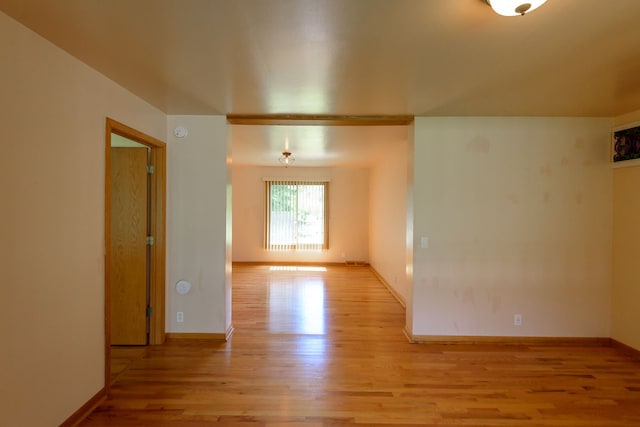 empty room with baseboards and light wood-style flooring