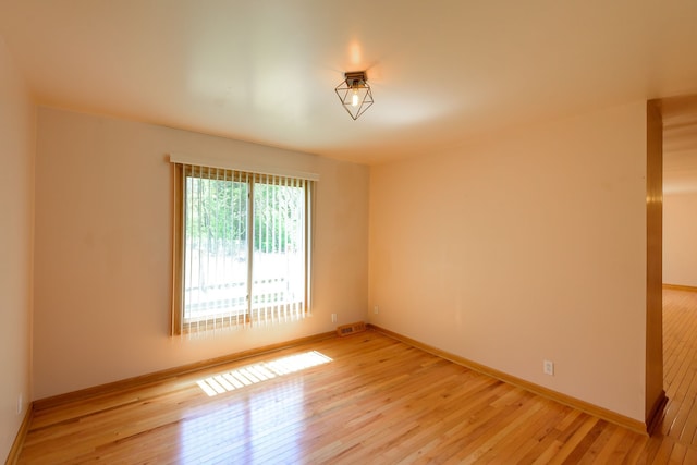 spare room featuring baseboards, visible vents, and light wood-style floors
