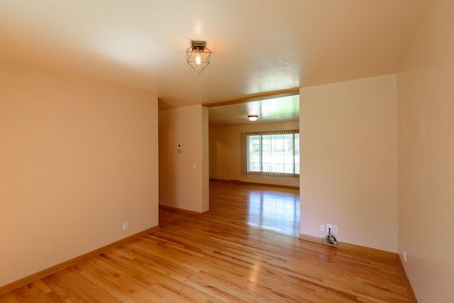 unfurnished room featuring baseboards and light wood finished floors