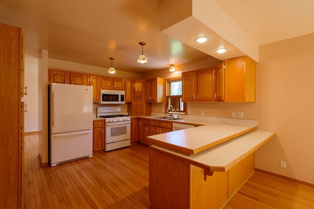 kitchen with a sink, white appliances, light wood-style flooring, a peninsula, and baseboards