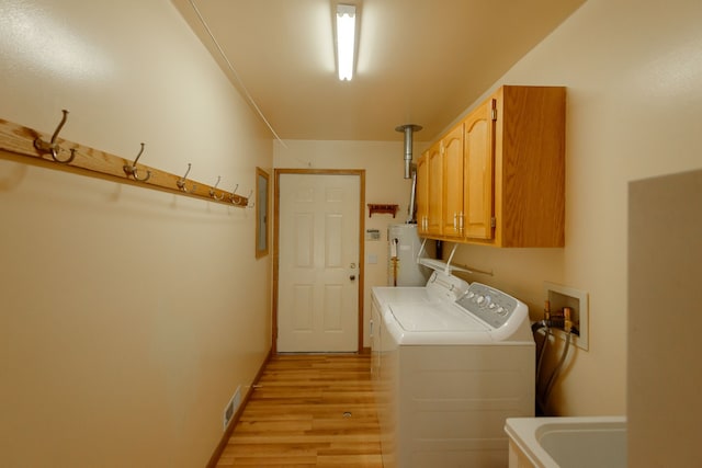 laundry room with cabinet space, light wood-style flooring, water heater, visible vents, and washing machine and dryer