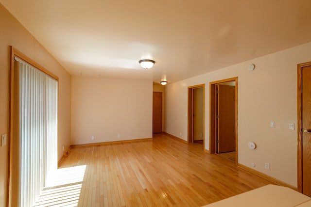 spare room with baseboards and light wood-type flooring