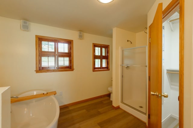 full bathroom featuring toilet, baseboards, wood finished floors, and a stall shower
