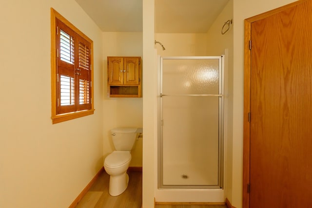 bathroom with baseboards, a stall shower, toilet, and wood finished floors