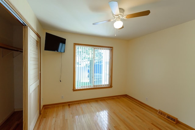 unfurnished bedroom featuring light wood-style floors, a ceiling fan, baseboards, visible vents, and a closet
