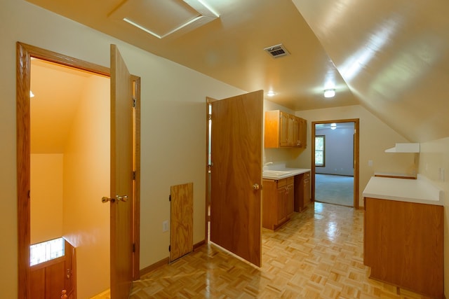 kitchen featuring visible vents, light countertops, baseboards, a sink, and lofted ceiling