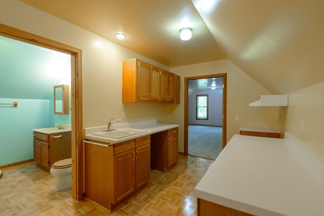 kitchen featuring a sink, light countertops, vaulted ceiling, and brown cabinets