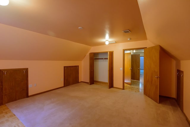 bonus room featuring light colored carpet, baseboards, visible vents, and vaulted ceiling