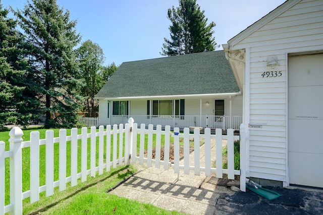 exterior space featuring a porch, a lawn, fence, and roof with shingles