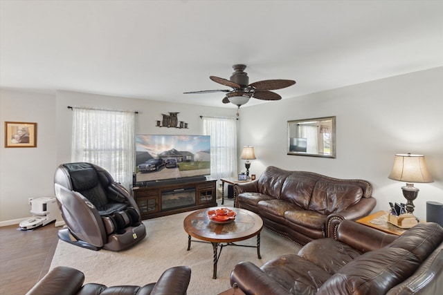 living area featuring baseboards, a ceiling fan, and wood finished floors