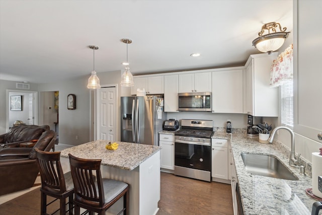 kitchen featuring white cabinets, stainless steel appliances, open floor plan, and a sink
