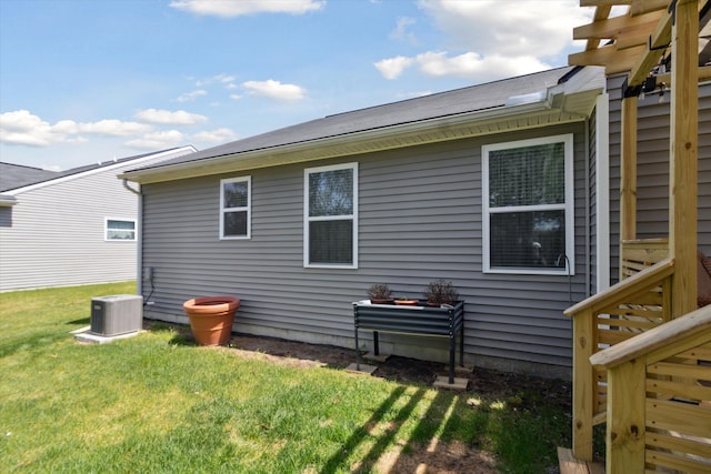 rear view of house with central AC unit and a yard