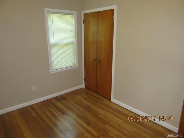 spare room featuring baseboards and wood finished floors