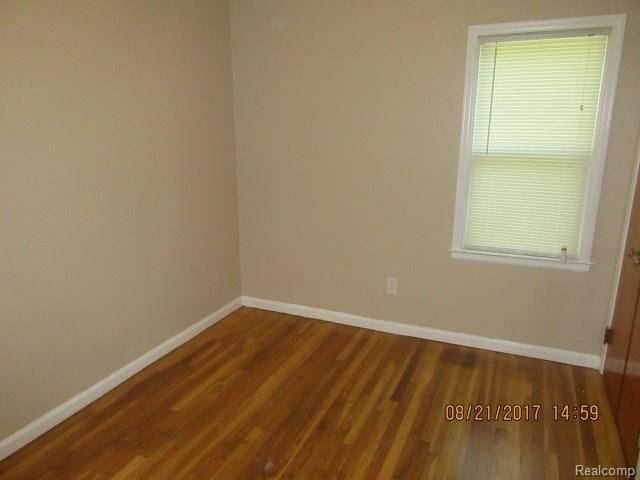 spare room featuring baseboards and wood finished floors