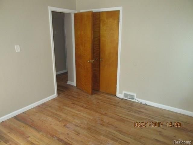 unfurnished bedroom with baseboards, visible vents, and wood finished floors