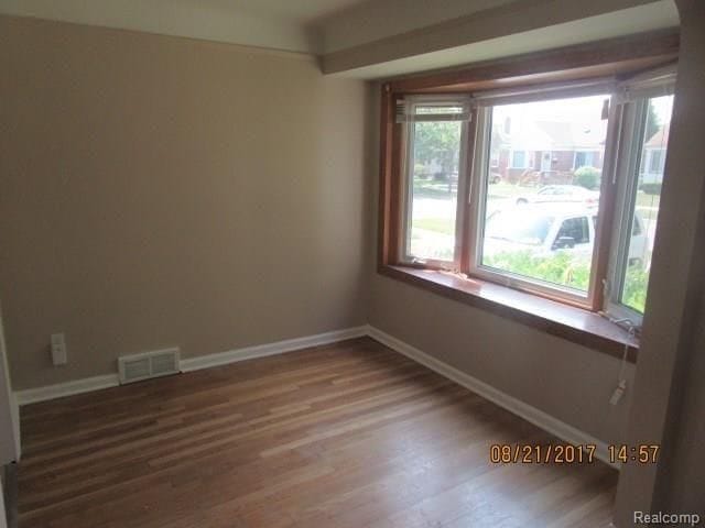 empty room with visible vents, wood finished floors, and baseboards