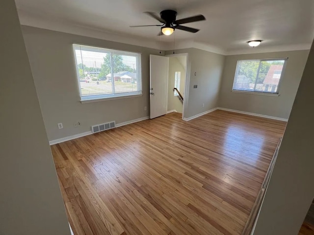 spare room with a ceiling fan, baseboards, visible vents, and wood finished floors