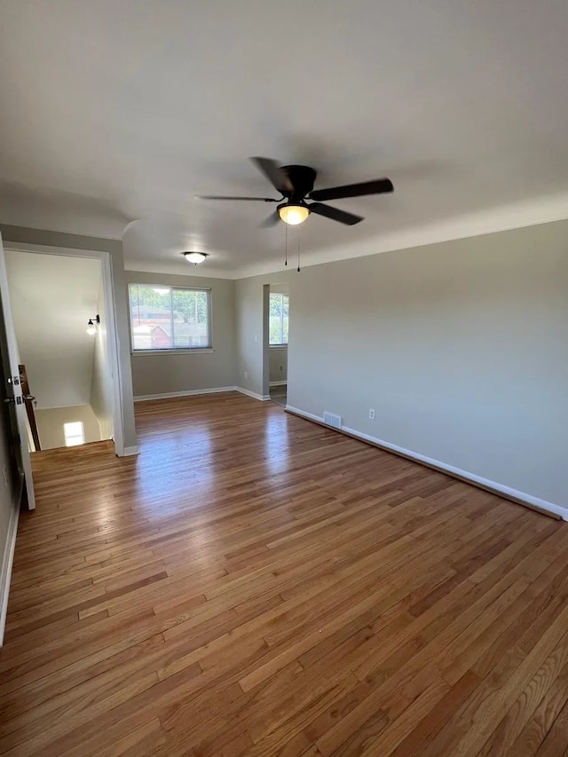 unfurnished room featuring baseboards, ceiling fan, wood finished floors, and visible vents